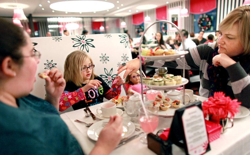 Deux adultes et une petite fille entrain de manger au restaurant American girl